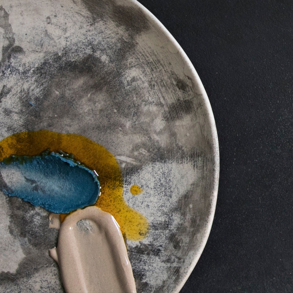 Close-up of a ceramic plate with textured surface and colorful glaze on a black background