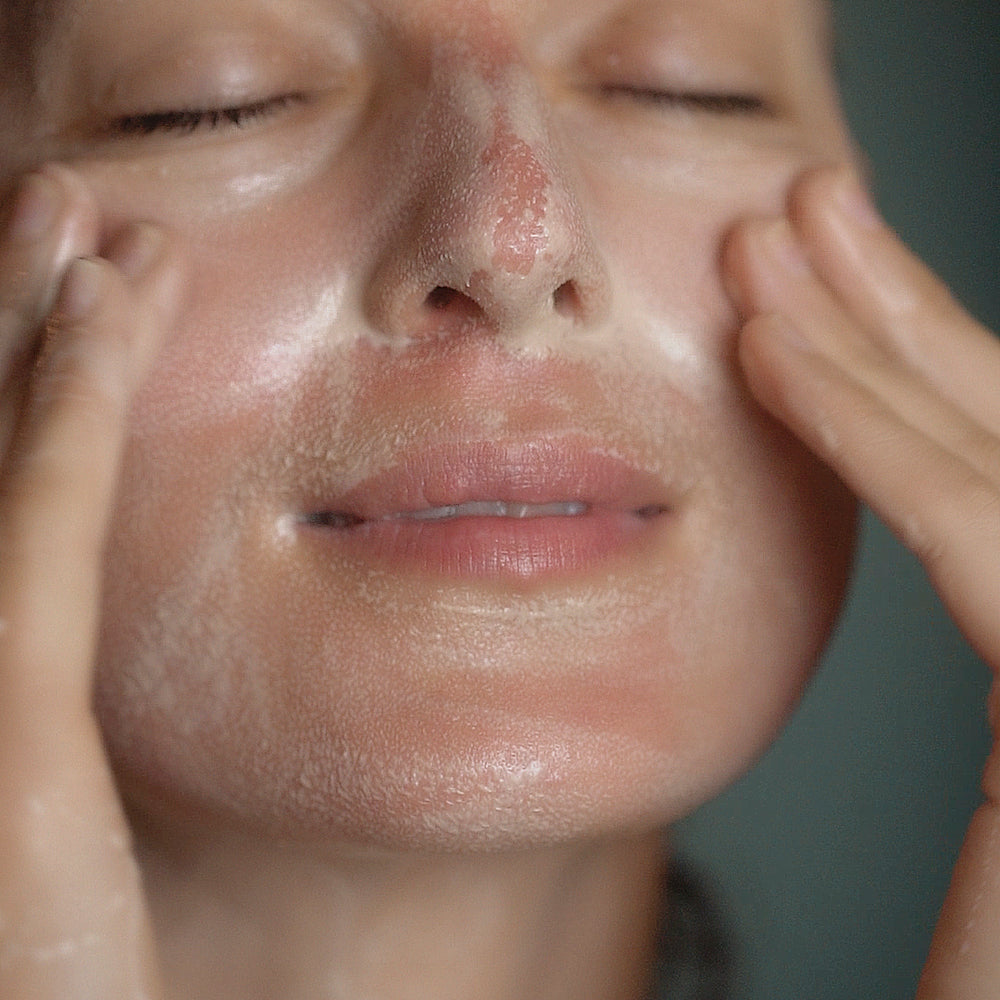 Close-up of a person applying a skincare product to their face.