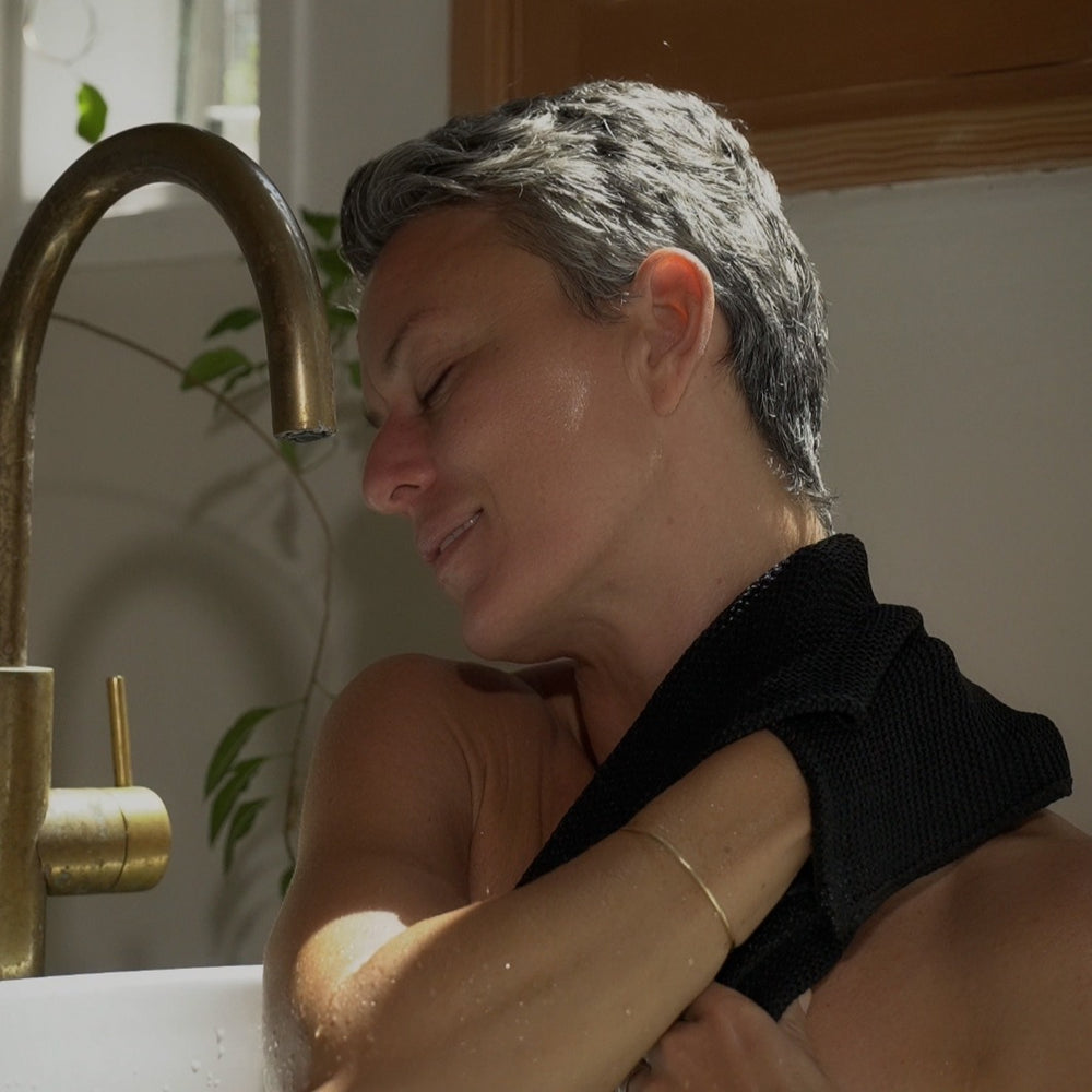 Person with a towel wrapped around their shoulders in a bathroom setting