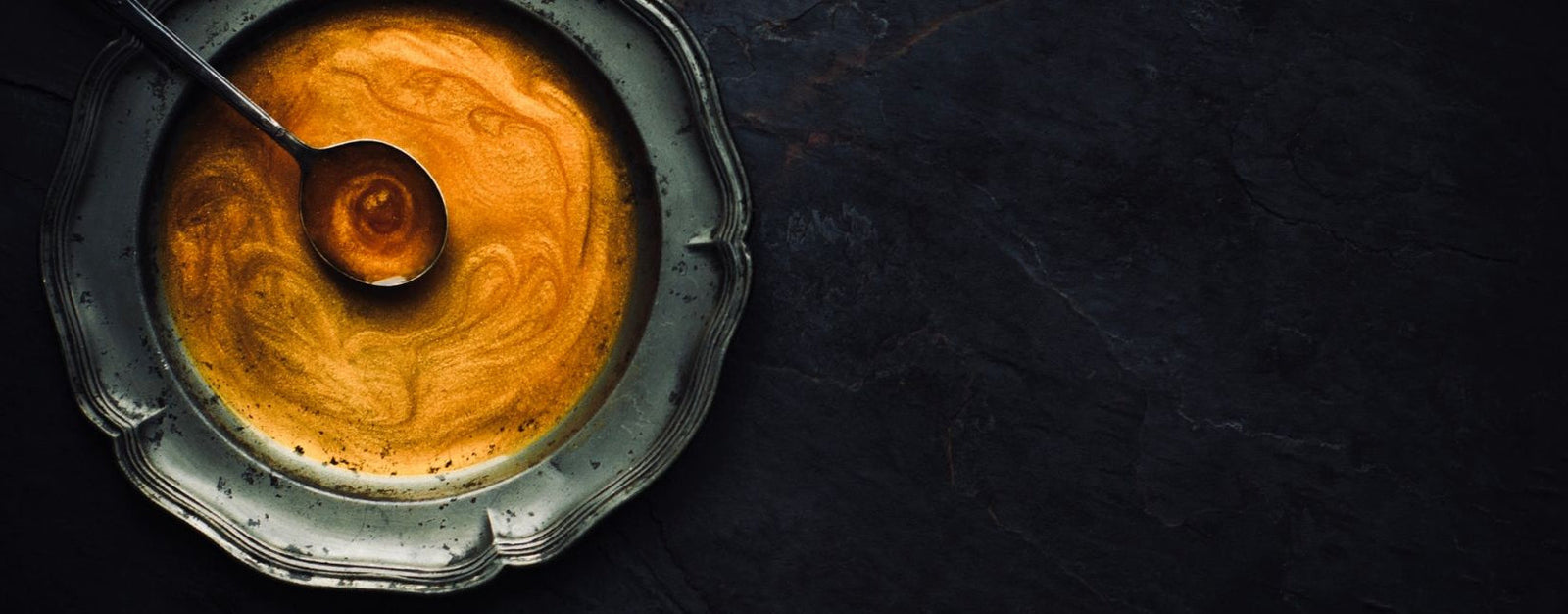 Close-up of a metallic object with warm oil in center on a dark background