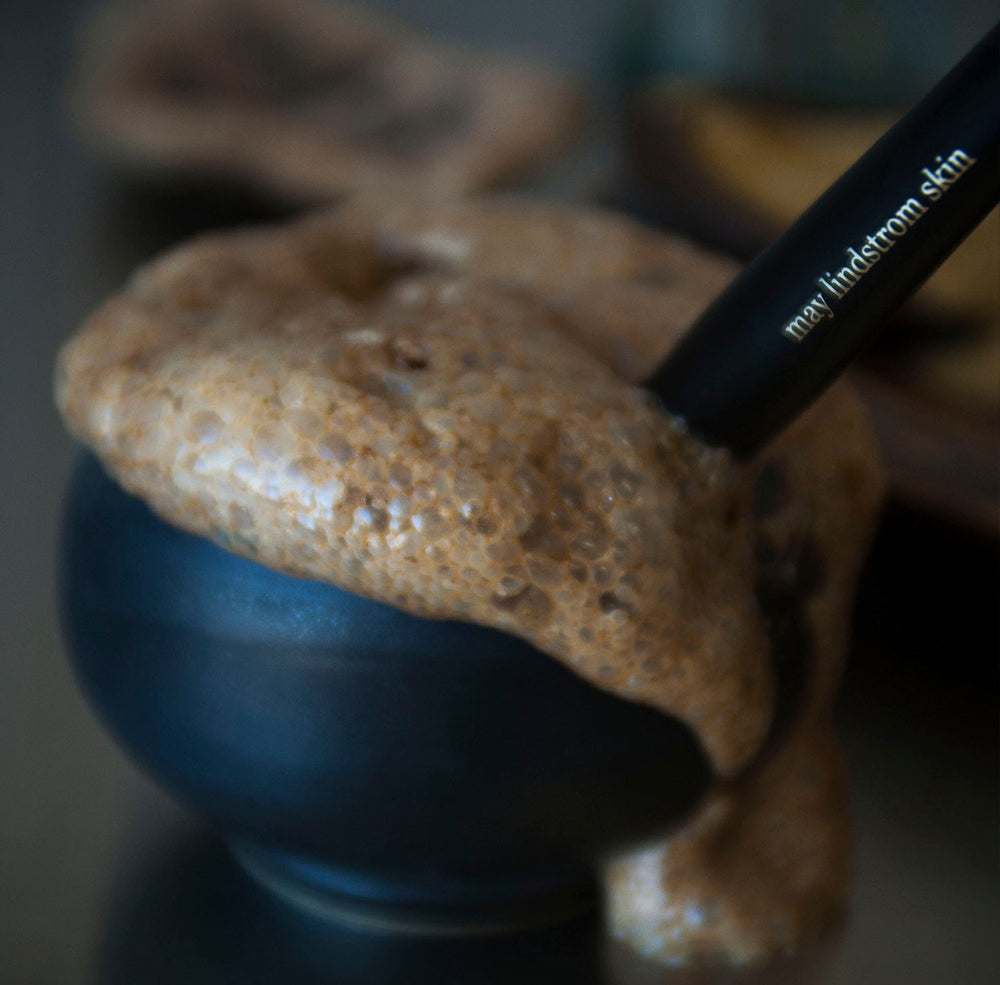 Cosmetic brush with 'max lindstrom skin' branding on a textured surface