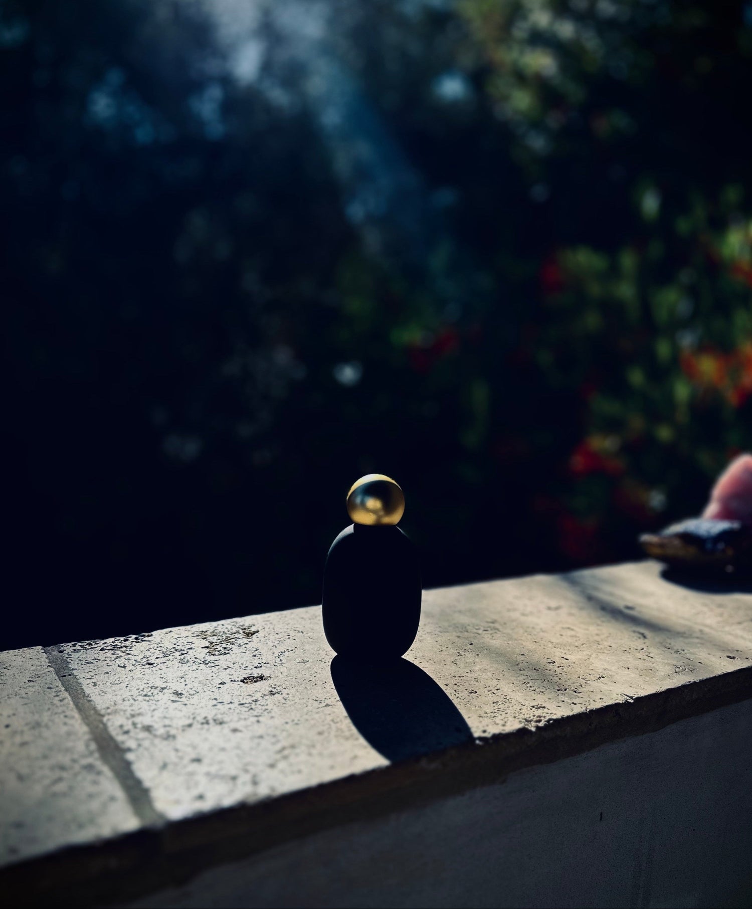Gold ball balanced on a black sphere on a textured surface with a blurred background