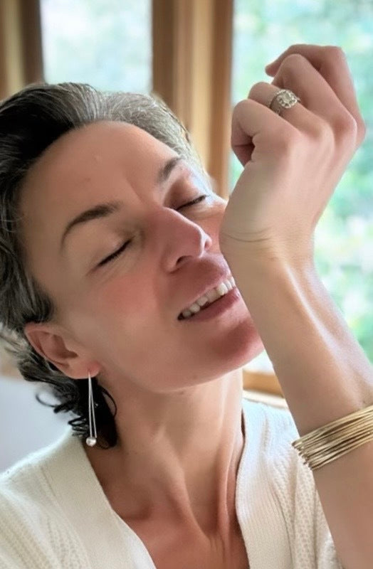 Woman with short hair and earrings, wearing a white top, indoors with natural light.