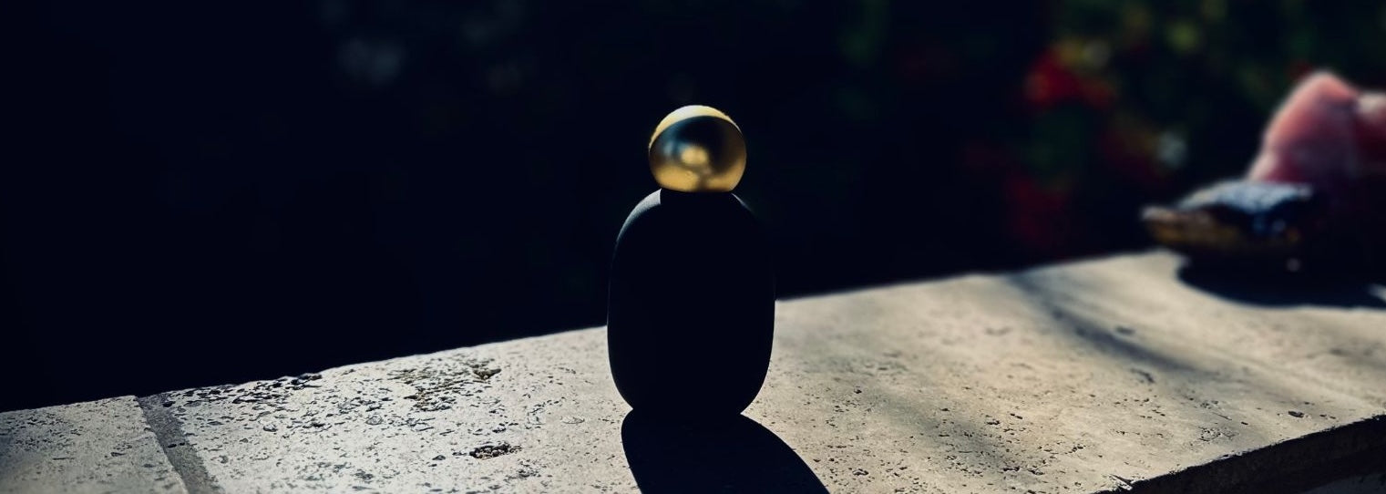 Gold ball balanced on a black sphere on a textured surface with a blurred background