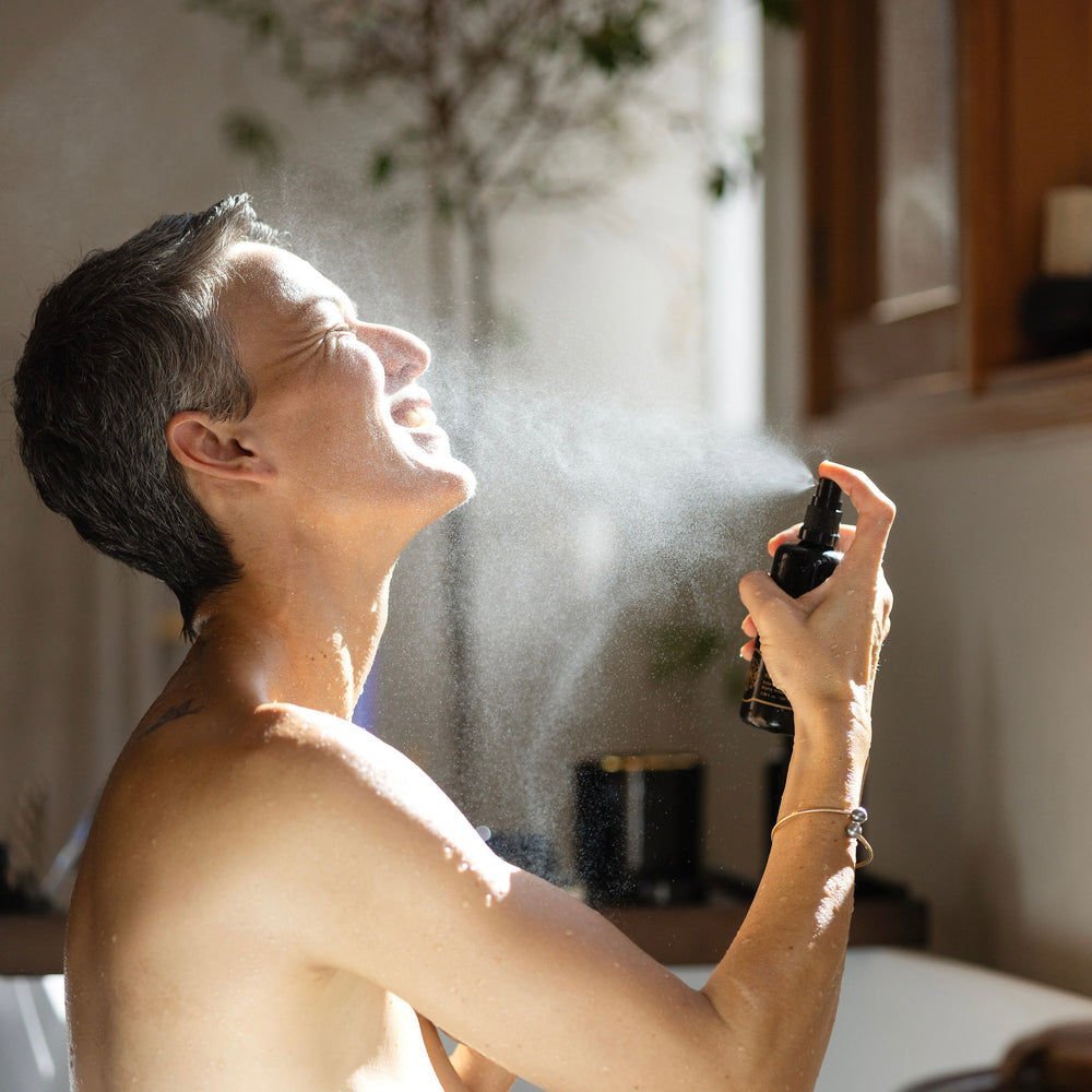 Person applying a spray to their face in a room with a blurred background