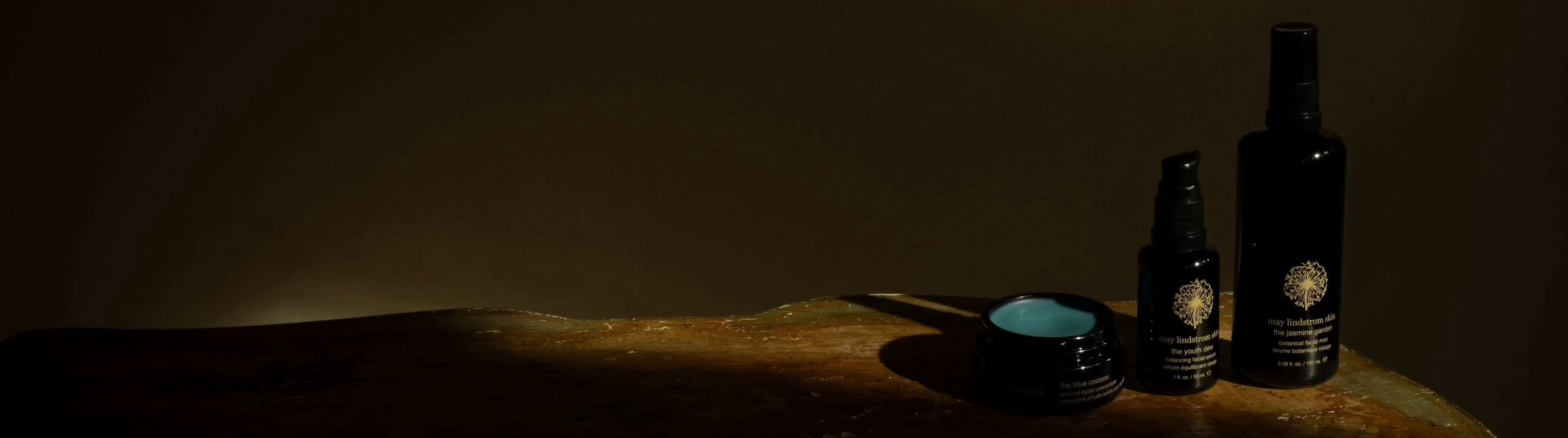 Three dark bottles with labels on a wooden surface against a dark background