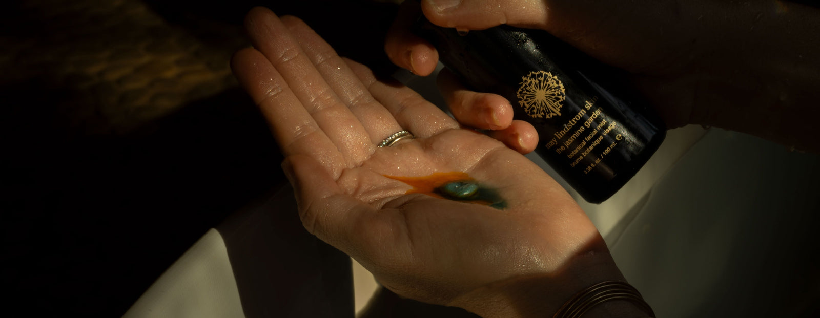 Hand holding a bottle of the jasmine garden with a dark background